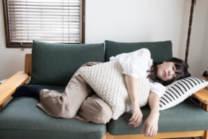 朝のリビングで、ソファに座って一息つく産後のママ