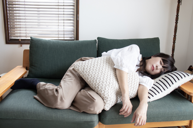 朝のリビングで、ソファに座って一息つく産後のママ